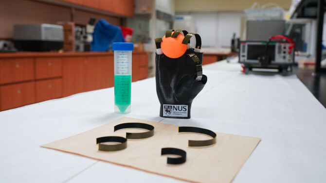 The wooden gripper holding an orange ball atop a table.